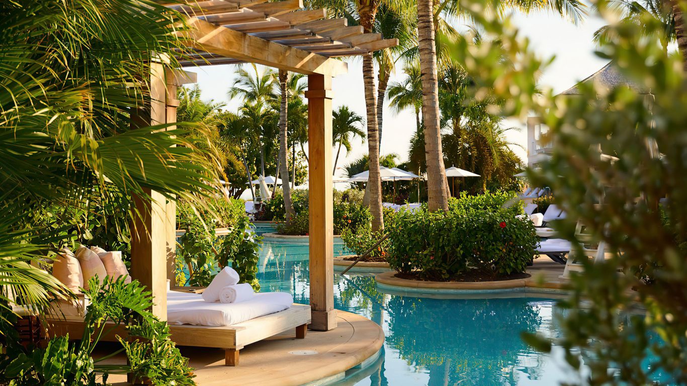 A luxury resort pool simulating a lagoon surrounded by lounge areas and greenery.